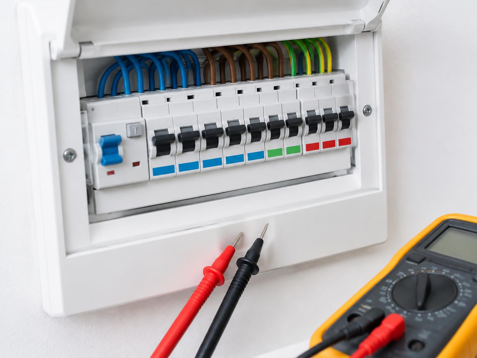 Modern consumer unit with labelled circuit breakers and a multimeter