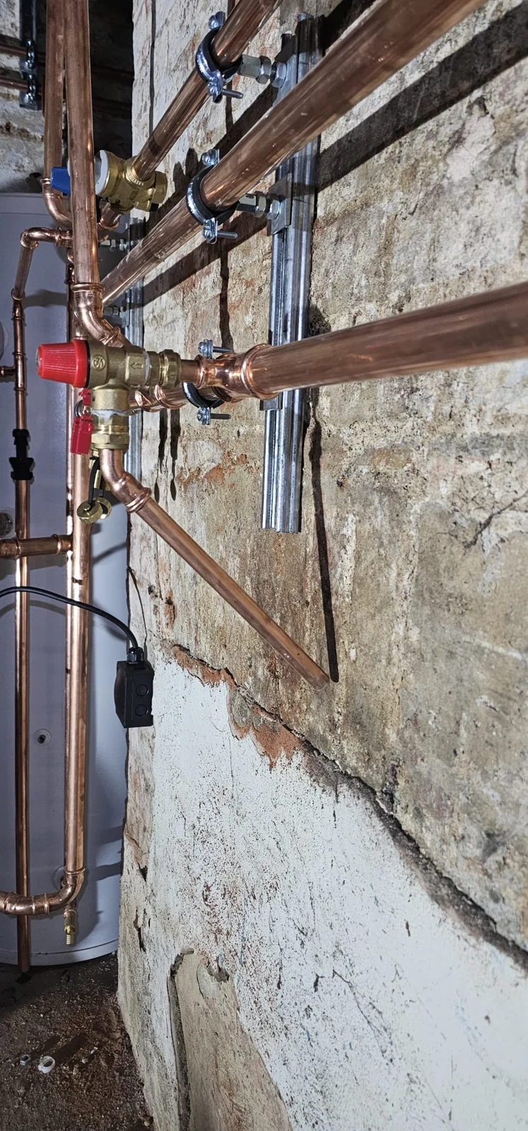 Copper pipe runs clipped to the exposed wall