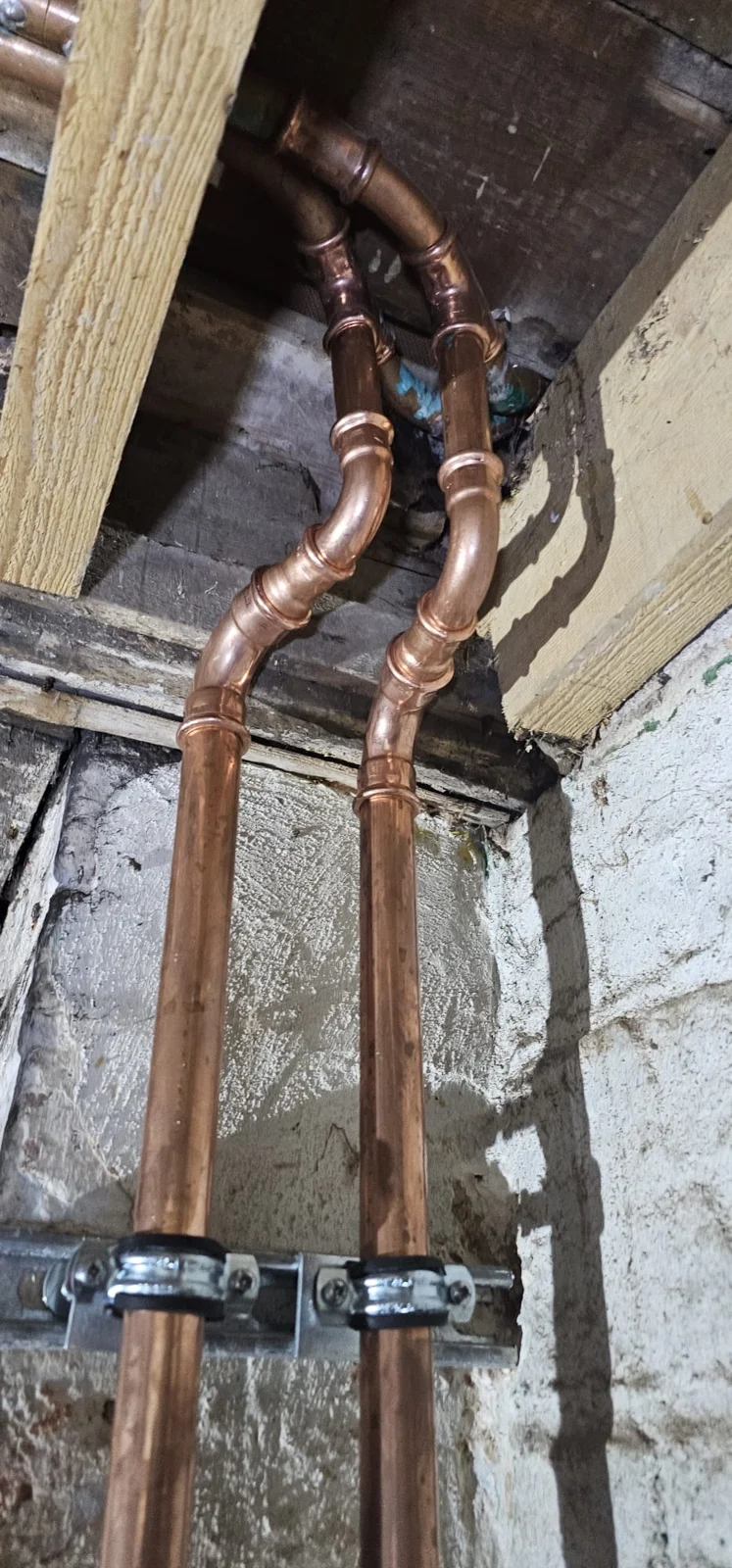 Copper pipes routed around a timber beam