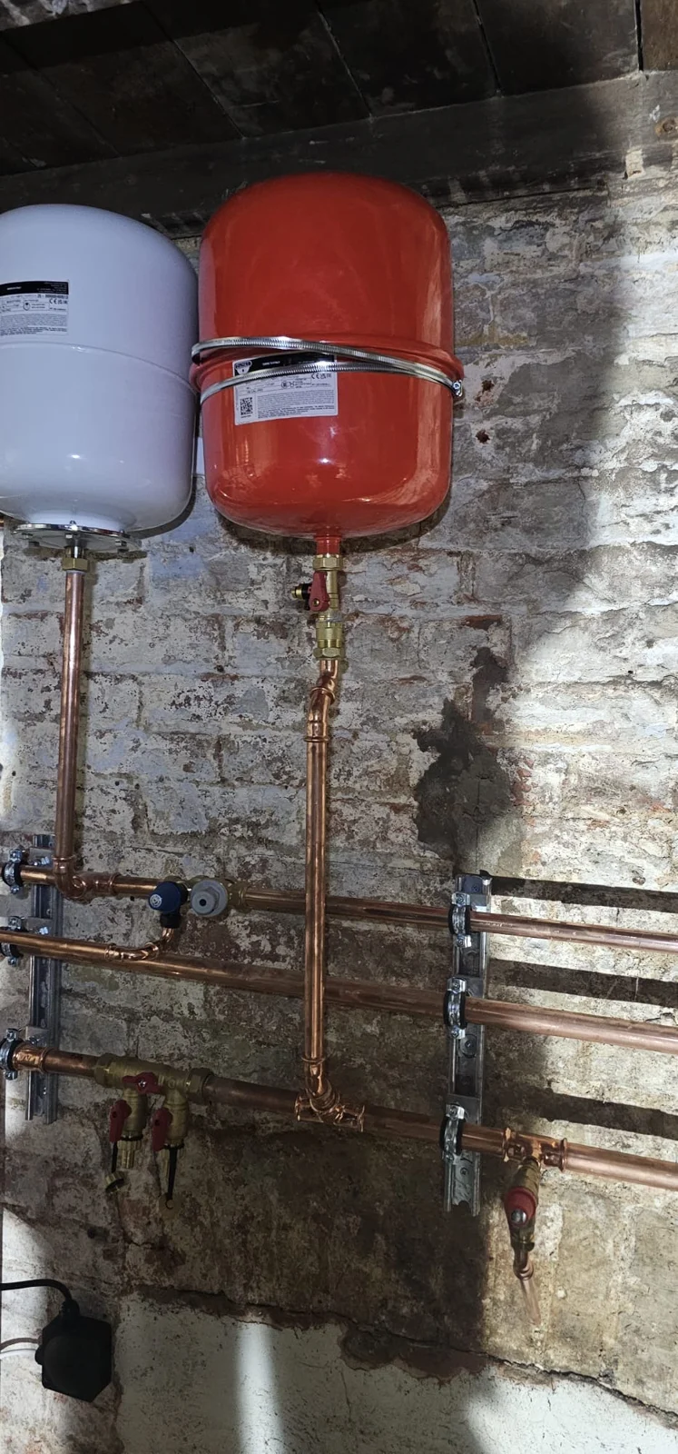 Red and white expansion vessels on the brick wall
