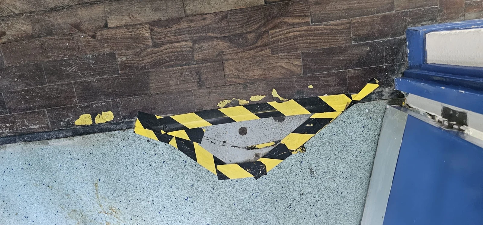Taped-off floor opening beside a blue doorway