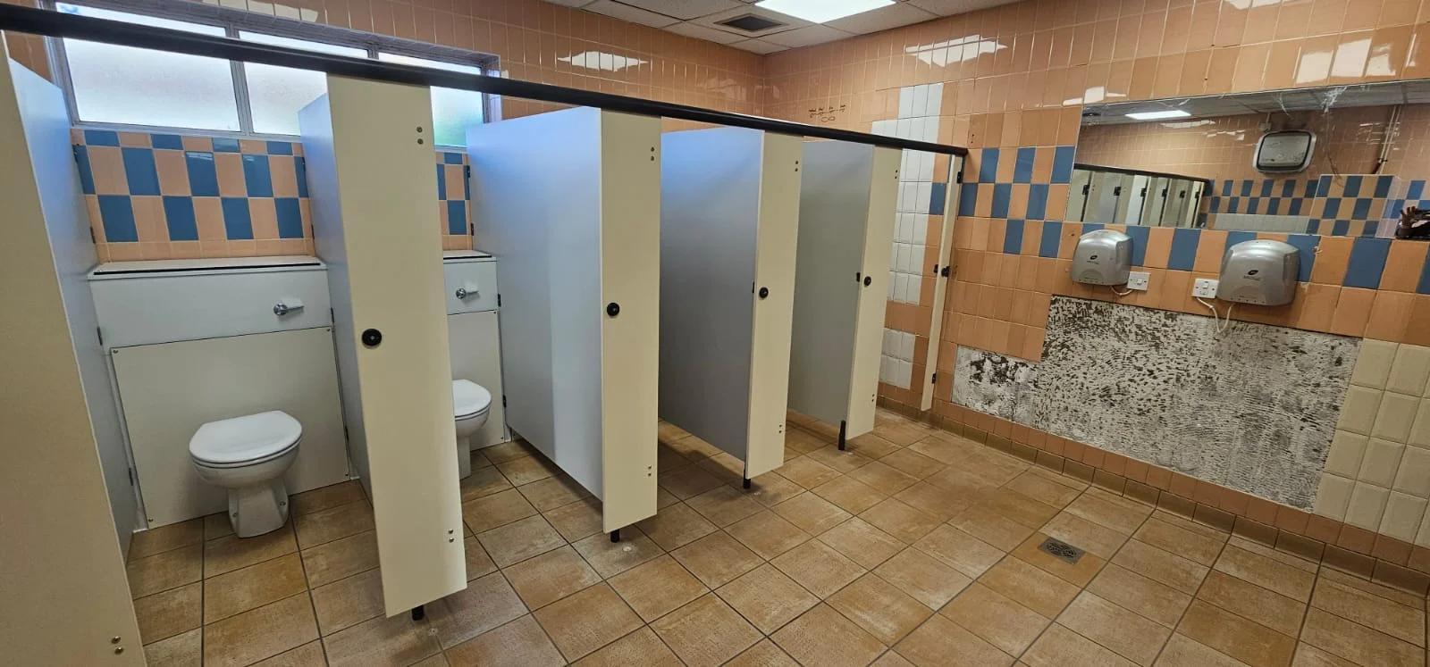 Cream cubicles and tiled washroom