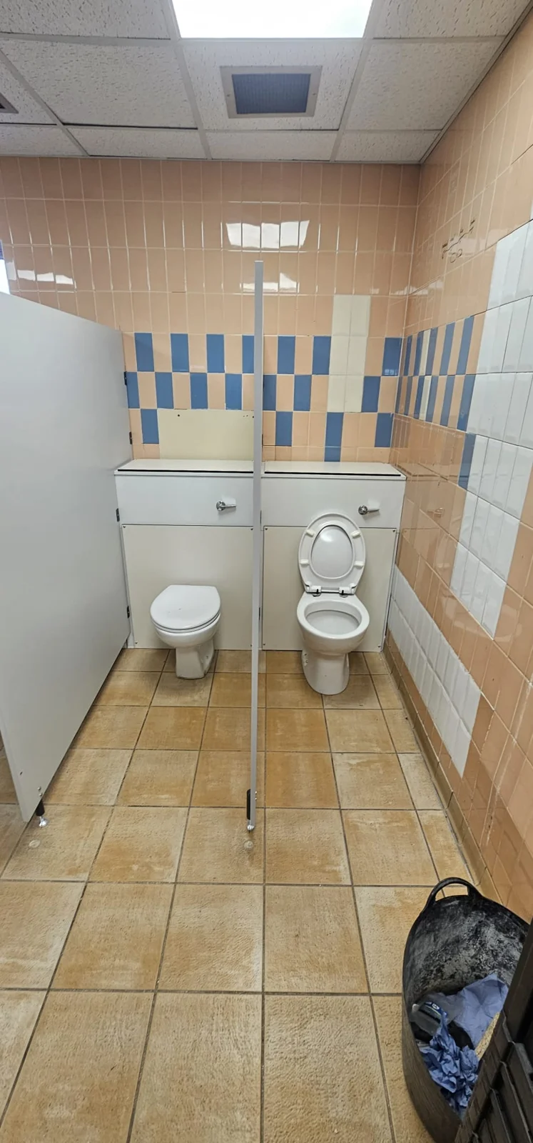 Two toilets against the tiled wall