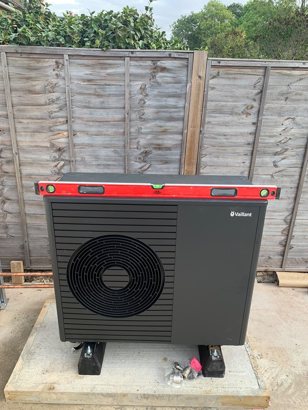 Outdoor air source heat pump unit on a concrete base in a garden, installed by Smart Eco Developments